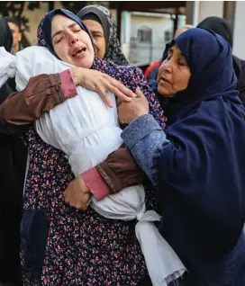  ?? ?? Horror: Relatives hold a tiny body after an air strike in Gaza