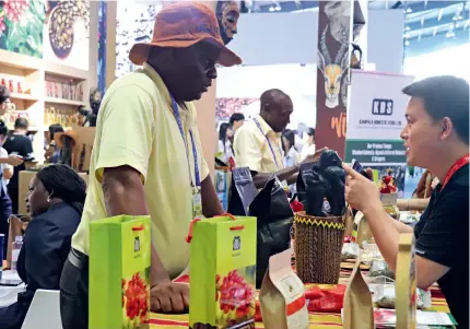  ?? (HU FAN) ?? A Ugandan exhibitor promotes co-ee to a visitor at the third China-Africa Economic and Trade Expo in Changsha, Hunan Province in central China, on 29 June