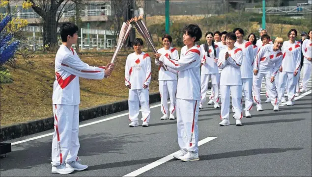  ??  ?? Azusa Iwashimizu, jugadora de fútbol de la Selección femenina de Japón campeona del mundo, pasa la llama olímpica a una estudiante de secundaria de Fukushima, Asato Owada.