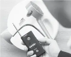  ?? — AFP photo ?? This picture shows a police official testing a detector in front of a hidden mini-camera installed in a hair-dryer holder as South Korean police talk to the media about the latest spycam-related crime at the Korean National Police Agency in Seoul.