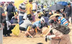  ?? APICHART JINAKUL ?? People turn up in droves to collect blessed rice seeds, which they will keep as sacred items.