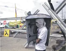  ??  ?? Un manifestan­te se protege en un bloqueo de carretera, durante las protestas en Cali.