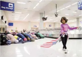  ??  ?? A girl dances while women pray during a protest against the travel ban at Dallas/Fort Worth Internatio­nal Airport while protesters rally at San Francisco Internatio­nal Airport on Sunday.