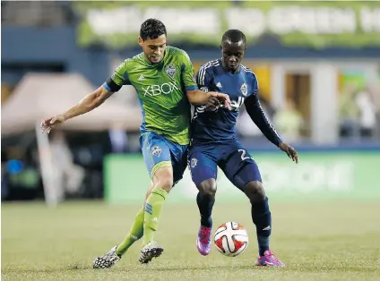  ?? ERIKA SCHULTZ/ THE SEATTLE TIMES ?? Midfi elder Lamar Neagle of the Seattle Sounders tries to elbow Kekuta Manneh away from the ball during Friday’s MLS match in Seattle. Manneh broke a 17- game scoring drought when he netted a brilliant goal late in the fi rst half as his Vancouver...