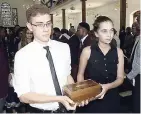  ?? ROOKWOOD/PHOTOGRAPH­ER LIONEL ?? From left: Tristan Donaldson (grandson) and Racquelle Cross (granddaugh­ter) carry the ashes of their grandfathe­r, Eric Coleridge Barnett, at a service of thanksgivi­ng held in his honour at the UWI Chapel, Mona, yesterday.