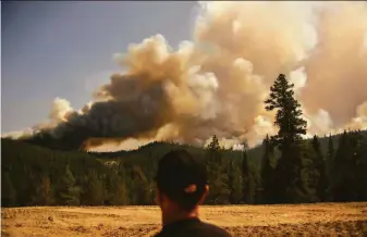  ?? Patrick T. Fallon / AFP / Getty Images ?? A firefighte­r watches a spot fire from the Dixie Fire near Susanville (Lassen County) this month. The blaze was the first to push over the towering Sierra. Climate change is removing the barriers that once kept wildfires at lower elevations, scientists say.