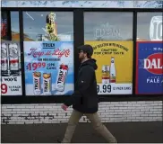  ?? HELEN H. RICHARDSON — THE DENVER POST ?? A pedestrian walks past advertisem­ents for liquor at a local liquor store along Colfax avenue in Denver on Jan. 3, 2024. Colorado has a high rate of alcohol-related deaths, ranging from car crash fatalities to suicide deaths and liver failure. Colorado’s alcohol-related deaths increased by about 27% in the first year of the pandemic, from 2,405 deaths in 2019 to 3,051 in 2020, according to a study by researcher­s at the National Institute on Alcohol Abuse and Alcoholism.