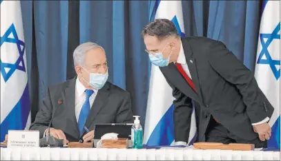  ?? Gali Tibbon The Associated Press ?? Benjamin Netanyahu listens Sunday to a Cabinet official in Jerusalem. Israel is undertakin­g more coronaviru­s restrictio­ns.