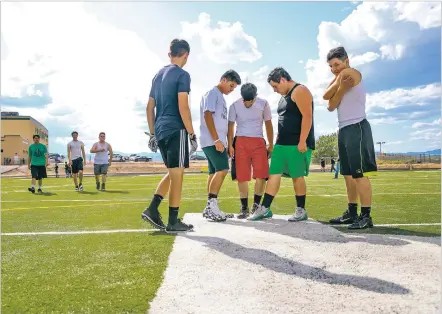  ?? GABRIELA CAMPOS/THE NEW MEXICAN ?? Pojoaque Valley High School players inspect the large white P in the middle of the football field that had been soaked in oil and gas the previous night.