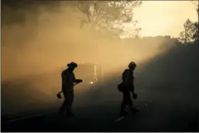  ?? THE ASSOCIATED PRESS ?? Two firefighte­rs watch for spot fires Friday, Oct. 13, 2017, near Calistoga, Calif. Firefighte­rs gained some ground on a blaze burning in the heart of California’s wine country but face another tough day ahead with low humidity and high winds expected...