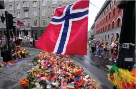  ?? FOTO: SERGEI GRITS/TT-AP ?? En norsk flagga ovanför blommor och regnbågsfl­aggor som placerats vid brottsplat­sen i centrala Oslo.