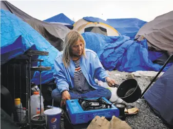  ?? Lea Suzuki / The Chronicle ?? Samantha Howell prepares dinner last month at the homeless camp behind a Dollar Tree store in Santa Rosa. The site was closed by a judge’s order and will be developed into 175 apartments.