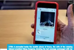  ?? —AFP ?? LYON: A journalist holds the mobile phone of Grace, the wife of the missing Interpol president Meng Hongwey, showing the last message exchanged with her husband, during a press conference in Lyon.