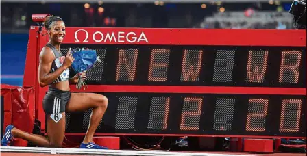  ??  ?? roud Kendra Harrison poses for a photograph with the clock showing her new world record time of 12.20 she clocked in winning the 100m hurdles final at the Olympic Stadium in London on Friday. — AFP