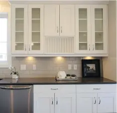  ??  ?? The shaker style maple cabinets are painted white. For traditiona­l appeal, the builder added a plate rack and vintage bubble glass to the cabinet doors.