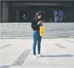  ??  ?? People use their mobile phone outside a building in Beijing.The NDRC will scrap restrictio­ns in cities of 1 to 3 million on coveted household registrati­on permits for out-of-towners, which include migrant workers and college graduates. — AFP photo