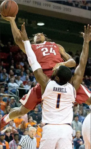  ?? AP/BRYNN ANDERSON ?? Arkansas guard Michael Qualls (24) goes over Auburn’s KT Harrell (1) in the first half for two of his 19 points in the Razorbacks’ 101-87 victory over the Tigers at Auburn Arena in Auburn, Ala.