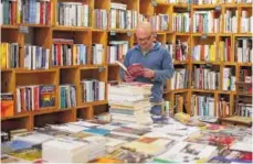  ?? ASSOCIATED PRESS FILE PHOTO ?? Vitor Rodrigues picks up a book titled “Vencer o Medo,” or “To Defeat Fear,” by union leader Manuel Carvalho da Silva at his bookshop in Lisbon.