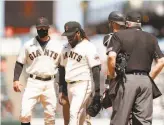  ?? Ezra Shaw / Getty Images ?? Johnny Cueto (center) removes himself in the sixth inning, with help from Gabe Kapler, after experienci­ng lat tightness.