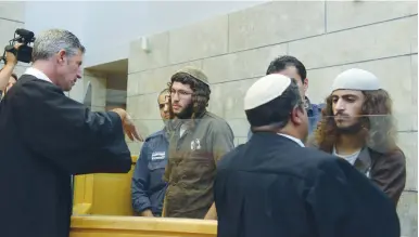  ?? (Basel Awdat/Flash 90) ?? YEHUDA ASRAF (left) and Yinon Reuveni, suspected of vandalizin­g the Church of the Multiplica­tion of the Loaves and Fishes, speak to their lawyers in the Nazareth Magistrate’s Court yesterday.