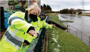  ??  ?? Visit: Boris Johnson at flood gates by the river at flood-hit Didsbury