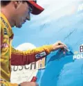  ??  ?? NASCAR Cup Series driver Joey Logano signs the pole award wall Friday after qualifying first for the Hollywood Casino 400 at Kansas Speedway.