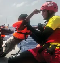  ??  ?? I’ve got you: A charity worker lifts a child to safety