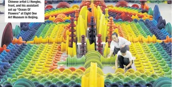  ??  ?? Chinese artist Li Hongbo, front, and his assistant set up “Ocean Of Flowers” at Eight One Art Museum in Beijing.