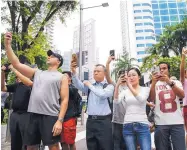 ?? YONG TECK LIM/ASSOCIATED PRESS ?? Members of the public take photos of the motorcade of North Korean leader Kim Jong Un as it leaves the St. Regis Hotel in Singapore on Tuesday.
