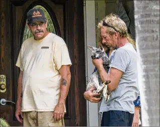  ?? PHOTOS BY RICHARD GRAULICH / THE PALM BEACH POST ?? Scott Griffith holds Blaze, one of the seven kangaroos that stay at a Jupiter Farms sanctuary, as friends and neighbors come to visit the marsupials returned by the Florida Fish and Wildlife Conservati­on Commission on Monday.