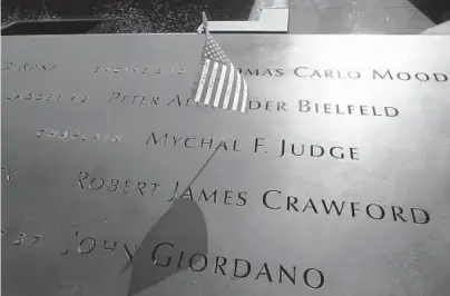  ?? MIKE SEGAR/AP 2011 ?? A flag in the etched name of Michal F. Judge, a fire chaplain who died in the 9/11 attacks on the Wold Trade Center.