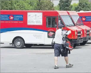  ?? CP PHOTO ?? A postal worker walks past Canada Post trucks at a sorting centre in Montreal. The federal government has appointed a mediator to work with both sides in the Canada Post labour dispute.