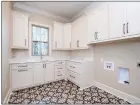  ?? ?? This laundry room provides a window, a countertop, cabinets and black-and-white decorative tile flooring.