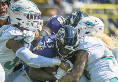  ?? JERRY JACKSON/BALTIMORE SUN ?? Ravens running back Justice Hill is tackled by a pair of Dolphins defenders during Sunday’s 42-38 loss at M&T Bank Stadium. Through two weeks, the Ravens are 13th in the NFL in rushing average (4.7 yards per carry), 18th in rushing offense (109.0 yards per game) and, maybe most alarmingly, last in Football Outsiders’ efficiency metrics.