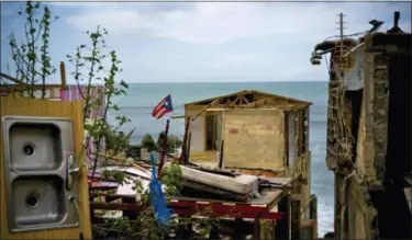  ?? RAMON ESPINOSA — THE ASSOCIATED PRESS ?? A Puerto Rican national flag is mounted on debris of a damaged home in the aftermath of Hurricane Maria in the seaside slum La Perla, San Juan, Puerto Rico.