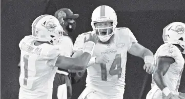  ?? PHELAN M. EBENHACK AP ?? Dolphins quarterbac­k Ryan Fitzpatric­k (14) celebrates with teammate Tua Tagovailoa, left, after throwing a touchdown pass against the Jaguars during the first half in Jacksonvil­le. Fitzpatric­k was 18 of 20 with two TD passes.