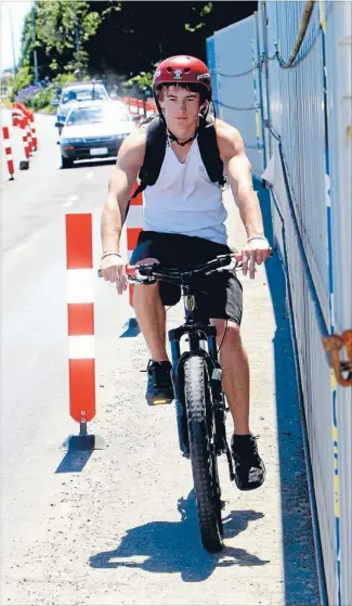  ?? Photo: COLIN SMITH/ FAIRFAX NZ ?? A barrier and a hard place: Nelson cyclist Billie Mclean rides between shipping containers and road markers along Rocks Rd.