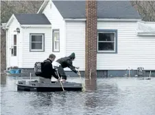  ?? MARK BUGNASKI/THE ASSOCIATED PRESS ?? People navigate on a flooded street in Niles, Mich., on Thursday. Flooding is expected to continue through the weekend in Michigan, Indiana and other Midwest states that have been swamped by high water from heavy rains and melting snow.