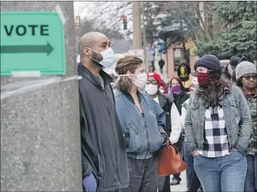  ?? Morry Gash Associated Press ?? VOTERS LINE UP at Riverside High School in Milwaukee. One man said he felt obligated despite the health risk because of Americans who fought and died for voting rights: “It would be a dishonor not to honor them.”