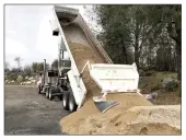  ?? ?? Rick Modrell, owner of Modrell Transporta­tion, dumps a load of 22 tons of sand in the parking lot Thursday (bottom left).