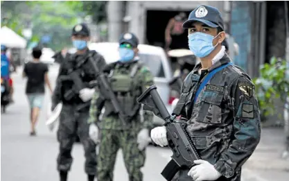  ?? —AFP ?? LOCKDOWN ENFORCERS Armed police in combat uniform and protective gloves man a road checkpoint in Cebu City to enforce a strict lockdown on the city that has seen a surge in the number of COVID-19 cases. Close to 1,000 policemen from other regions, including 160 commandos from the Special Action Force, have arrived in the city to assist its 1,200-strong police force.