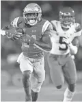  ??  ?? UCLA receiver Theo Howard runs after a catch ahead of Arizona’s Christian Young on Saturday.