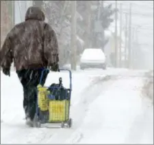  ?? ASSOCIATED PRESS ?? A woman pulls a cart filled with items purchased at a nearby store as she treks through the snow along East 2nd Street near Taylor Court in Hazleton while on her way home Wednesday.
