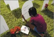  ?? LYNNE SLADKY — THE ASSOCIATED PRESS ?? Kyla Harris, 10, writes a tribute to her grandmothe­r, Patsy Gilreath Moore, who died at age 79 of COVID-19, at a symbolic cemetery last month of Miami. Thursday, there were over 3,000 American deaths.