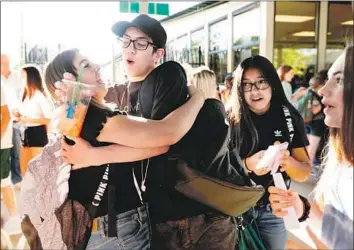  ?? Photograph­s by Genaro Molina Los Angeles Times ?? QWYNN BAKER, center, hugs Rylie Parris on Thursday, the first day of class at Paradise High School since the Camp fire tore through the town nearly nine months ago, killing 86 and destroying 14,000 homes.
