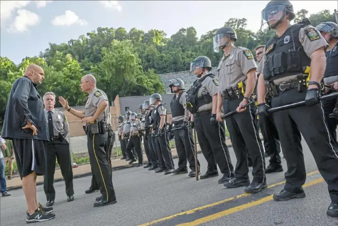  ?? Michael M. Santiago/Post-Gazette ?? John Fetterman, left, attempts to mediate between police and demonstrat­ors June 28, 2018, after the demonstrat­ors were blocked from marching along Electric Avenue in East Pittsburgh. Demonstrat­ors demanded Allegheny County District Attorney Stephen Zappala Jr. ask to reverse a judge’s decision on bail for the East Pittsburgh police officer who shot and killed 17-year-old Antwon Rose II.