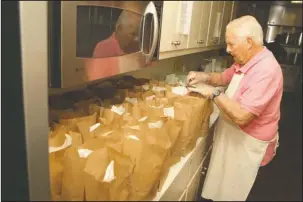  ?? The Sentinel-Record/Richard Rasmussen ?? LUNCHTIME: Volunteer Joe Lemmler prepares sack lunches at Jackson House on Tuesday.