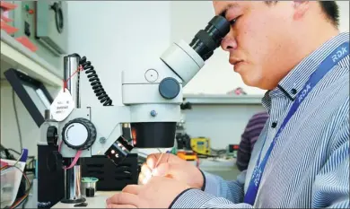  ?? REUTERS ?? A researcher uses a microscope during research work to design and develop a semiconduc­tor product at a Tsinghua Unigroup research center in Beijing.
