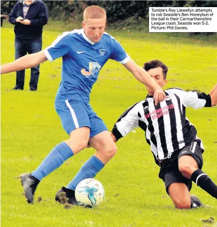  ??  ?? Tumble’s Roy Llewellyn attempts to rob Seaside’s Ben Honeybun of the ball in their Carmarthen­shire League clash. Seaside won 5-2. Picture: Phil Davies.