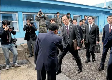  ?? PHOTO: AP ?? South Korean Unificatio­n Minister Cho Myoung-gyon, centre, shakes hands with a North Korean official as he crosses to North Korea for a meeting at the northern side of Panmunjom yesterday.